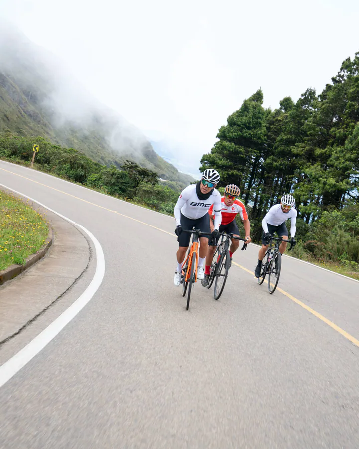 Tres ciclistas ascendiendo una carretera de montaña durante un entrenamiento ONE
